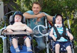 Richy Müller hockend zwischend zwei kleinen Jungen, die im Rollstuhl sitzen